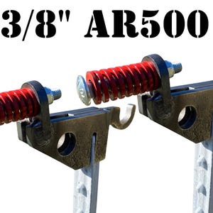 May include: Two 3/8" AR500 steel fence post brackets with red coil springs. The brackets are attached to gray metal fence posts.