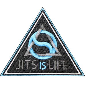 May include: A triangular embroidered patch with a black background and a light blue border. The design features a grey triangle overlapping a light blue stylized letter S. The text JITS IS LIFE is embroidered in grey and light blue at the bottom.