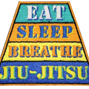 May include: A trapezoidal embroidered patch featuring four horizontal bands of color. The text reads EAT in white on teal, SLEEP in blue on orange, BREATHE in orange on yellow, and JIU-JITSU in yellow on blue. The entire patch has a thin orange border.