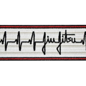 May include: A rectangular embroidered patch featuring a white background with horizontal light gray lines. A black heartbeat EKG line runs across the center, incorporating the cursive text jiu jitsu. The patch has a thin red and black border.