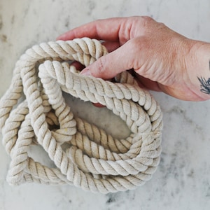 May include: A close-up of a thick, natural-colored rope, coiled and ready for crafting projects.