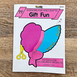 May include: A book titled "Gift Fun" with a pink and blue cut-out craft project of a woman wearing a hat. The book is for ages 3-6 and is part of the "Scissors Fun and Crafts" series.