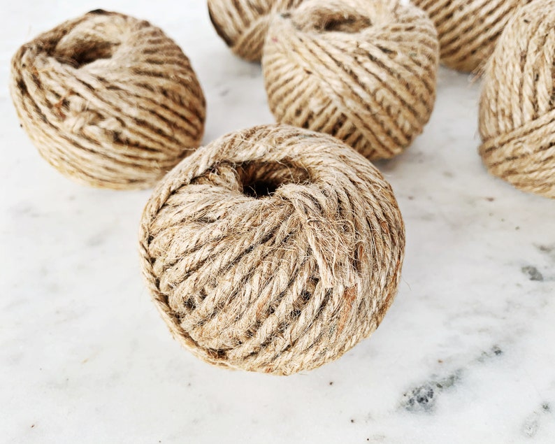 May include: Five balls of natural twine, each wound into a round shape. The twine is a light brown color and has a rough texture.