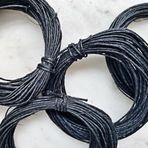 May include: Black twine string wound into three separate coils. The twine is thick and textured.