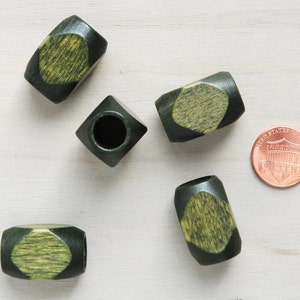 May include: Five wooden beads with a green and yellow colour scheme. The beads are in the shape of a cylinder with a diamond pattern on the top and bottom. The beads are approximately the size of a UK penny.
