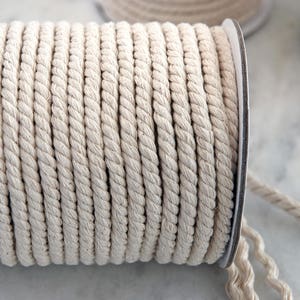 May include: A spool of natural cotton rope, wound tightly and ready to be used for crafting, macrame, or other projects.