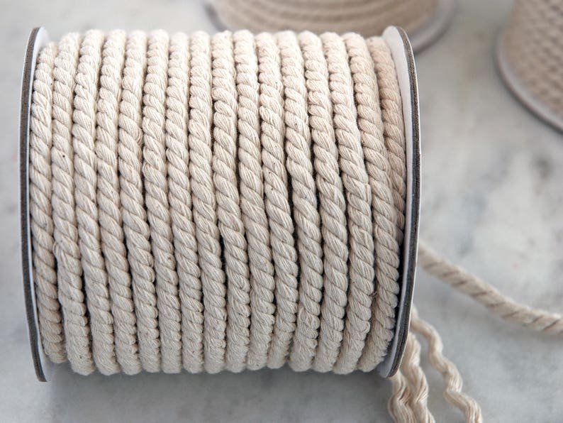 May include: A spool of natural cotton rope, wound tightly and ready to be used for crafting, macrame, or other projects.