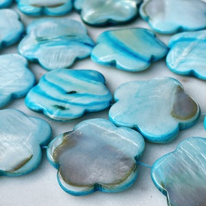 16" streng van 27 mm blauwe schelpkralen in een afgeronde bloemvorm. Inclusief 15 stuks.