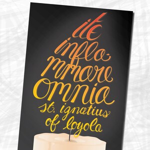 Puede incluir: Un póster en blanco y negro con un diseño de llama de vela amarilla y naranja. El texto dice "We inflo mmore Omnia St. Ignatius of Loyola" y "24" x 36" Poster Satin Poster Paper - St. Ignatius".
