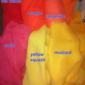 以下が含まれることがあります： red flame、orange、tangerine、carrot、coral、yellow squash、mustardというテキストがラベル付けされた、様々な暖色系の折り畳まれた布のロールのコレクション。テキスタイル素材は軽量で半透明に見え、柔らかな質感があります。