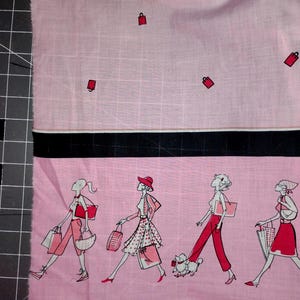May include: Pink fabric with a black stripe and illustrations of women shopping. The top portion has scattered red shopping bag icons. The bottom section features four women in stylish outfits, carrying bags and a poodle.