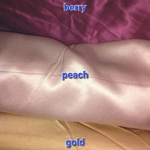 May include: Close-up of three fabric swatches in berry, peach, and gold. The berry swatch is a deep, rich purple. The peach swatch is a soft, light pink. The gold swatch is a warm, metallic tone. The word "berry", "peach", and "gold" are written on each swatch.