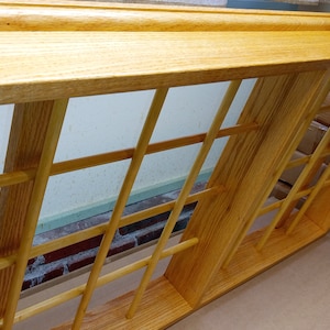 May include: A wooden frame with a grid pattern, made of light brown wood. The frame is empty and appears to be for display purposes.