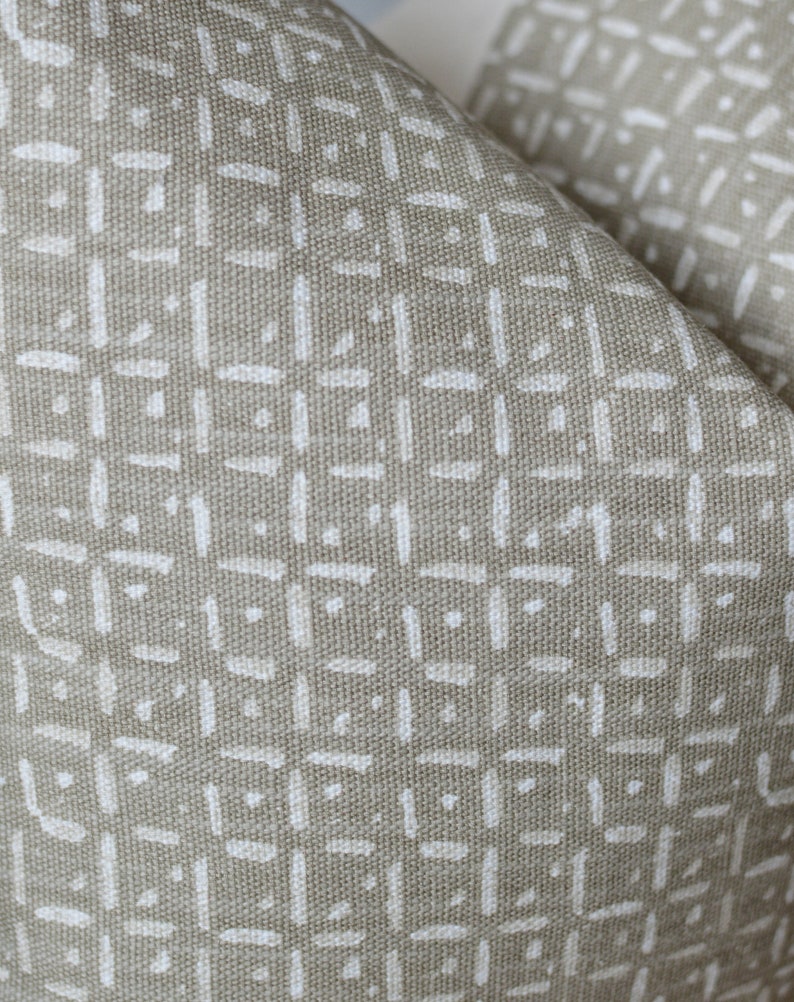 Peut inclure: Gros plan sur un tissu beige avec un motif g&eacute;om&eacute;trique blanc. Le motif est compos&eacute; de petites lignes fines qui cr&eacute;ent un design en forme de grille.