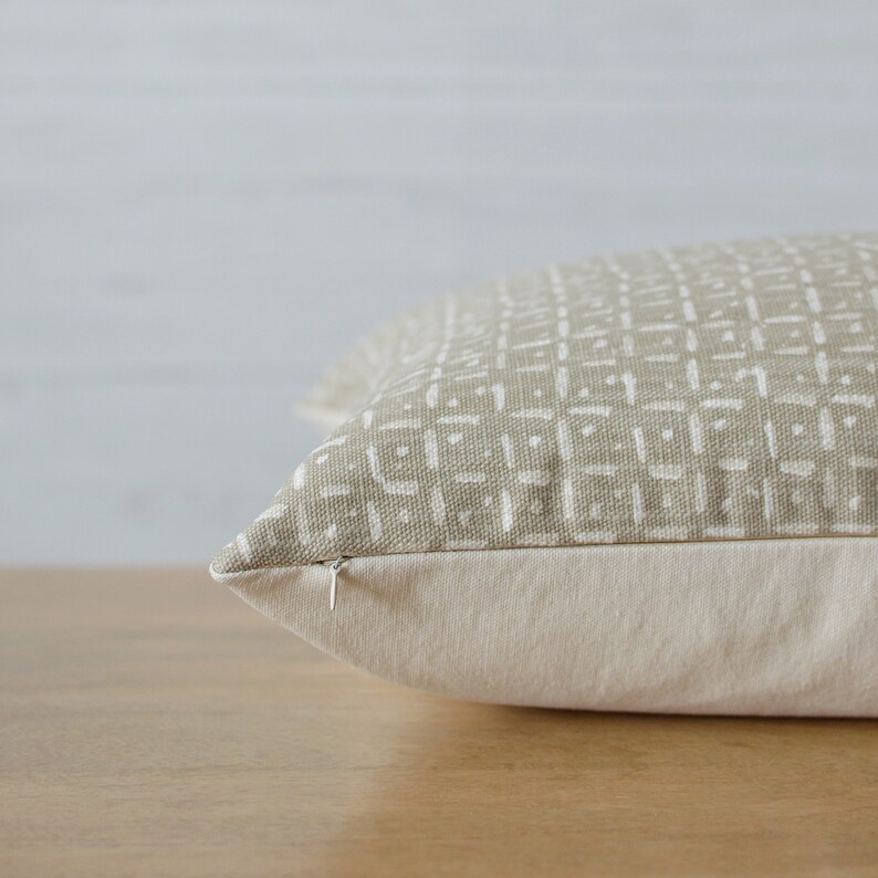 Peut inclure: Un coussin beige avec un motif g&eacute;om&eacute;trique blanc. Le coussin est dot&eacute; d'une fermeture &eacute;clair et est fabriqu&eacute; dans un tissu doux et confortable.