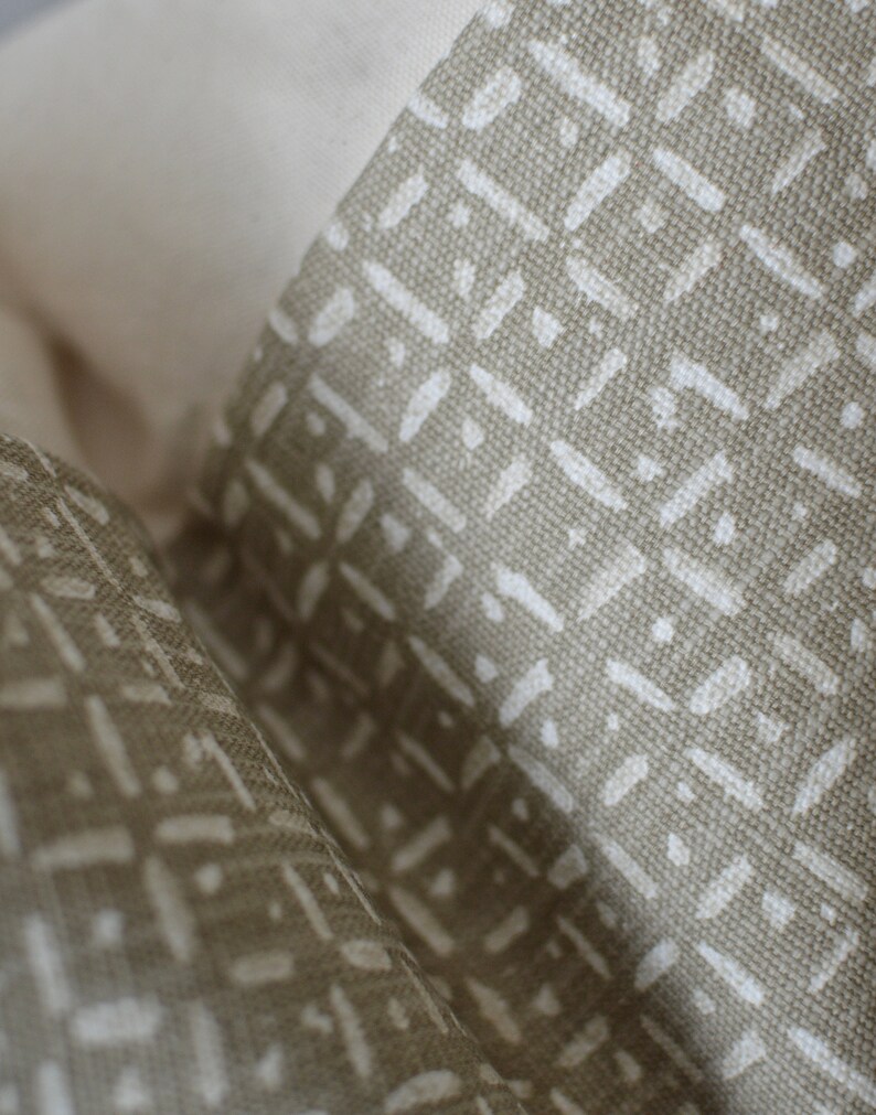 Peut inclure: Gros plan sur un tissu beige avec un motif g&eacute;om&eacute;trique blanc. Le tissu a une surface textur&eacute;e et un l&eacute;ger brillant.