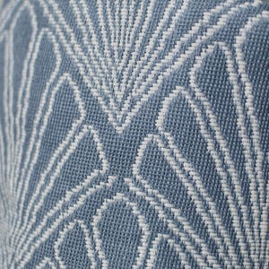 May include: Close-up of a blue and white woven fabric. The fabric features a repeating geometric pattern of white lines against a blue background. The texture appears to be a tight weave, suggesting a durable material suitable for upholstery or home decor.