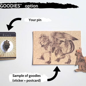 K&ouml;nnte beinhalten: Eine goldfarbene Emaille-Anstecknadel mit dem &auml;gyptischen Gott Osiris. Die Nadel befindet sich auf einem wei&szlig;en Hintergrund mit dem Text "EGYPTIAN GOD COLLECTION" und "O SIRIS". Die Nadel ist Teil einer "GOODIES"-Option, die auch eine Postkarte und einen Aufkleber enth&auml;lt. Die Postkarte zeigt eine Schwarzwei&szlig;illustration einer mythischen Kreatur mit Fl&uuml;geln und einen Hasenaufkleber.