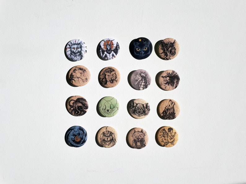 K&ouml;nnte beinhalten: Eine Sammlung von 16 runden, knopfartigen Pins mit verschiedenen Schwarzwei&szlig;illustrationen von Tieren und Fabelwesen. Die Pins sind in einem Rastermuster auf wei&szlig;em Hintergrund angeordnet.