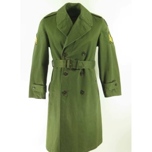 May include: A green double-breasted trench coat with a belt, epaulets, and buttoned cuffs. The coat has a classic design with a notched collar and a belt at the waist. The coat has a military style with a sergeant's stripes on the left sleeve.