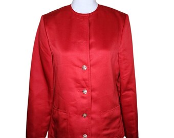 Puede incluir: Una chaqueta roja con cuello mandarín y cinco botones plateados. La chaqueta tiene dos bolsillos en la parte delantera.