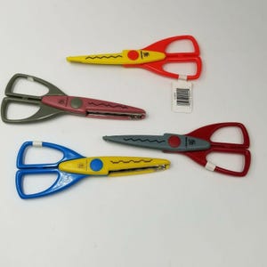 May include: Four pairs of decorative scissors in various colors: red, yellow, blue, and gray. Each pair has a different handle color and a wavy blade design. The scissors are designed for crafting and scrapbooking.