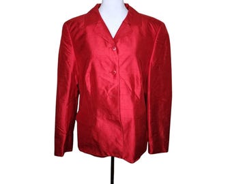 Puede incluir: Una chaqueta roja con cierre de botones y mangas largas. La chaqueta está hecha de un material sedoso.