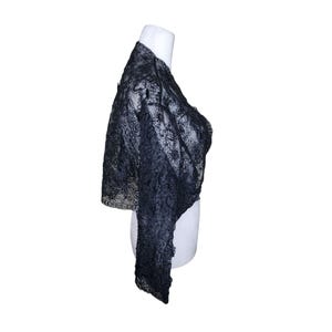 May include: A black lace shrug with a floral pattern. The shrug is on a white mannequin.