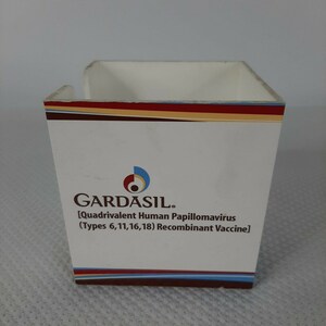 May include: A white, square container with the word "GARDASIL" printed on the front, along with the text "[Quadrivalent Human Papillomavirus (Types 6,11,16,18) Recombinant Vaccine]" and a logo. The top edge has a decorative stripe.