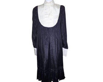 May include: A black dress with a white collar and cuffs. The dress has a pleated skirt and a fitted bodice.