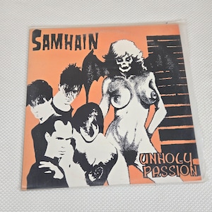 May include: A vinyl record album cover for the band Samhain. The cover features a black and white illustration of a skeletal figure with bat wings and several other figures. The album title "Unholy Passion" is printed in white.
