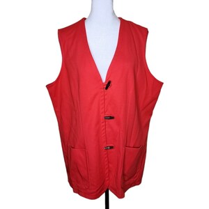 May include: A red sleeveless vest with a V-neck and three black button closures. The vest has two pockets on the front.