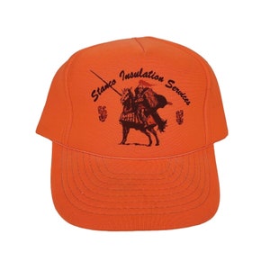 Könnte beinhalten: Orangefarbene Baseballkappe mit einem schwarz-weißen Logo eines Ritters auf einem Pferd. Das Logo lautet "Stanco Insulation Services".