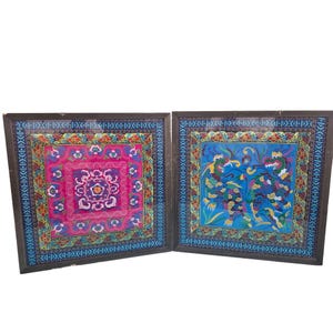 May include: Two framed Asian textile art pieces. One features a pink and purple floral design, the other a blue background with a dragon motif. Both have ornate borders in shades of blue, red, and green.
