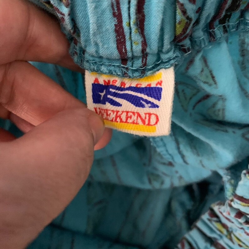 K&ouml;nnte beinhalten: Nahaufnahme eines blauen Stoffes mit wei&szlig;em Muster und einem gelben und blauen Etikett mit der Aufschrift "American Weekend".