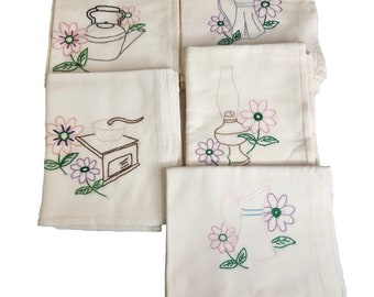 May include: Set of five white tea towels with embroidered floral designs and kitchen tools. The designs include a coffee grinder, a teapot, a lamp, and two pitchers.