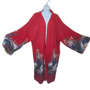 May include: A long red kimono with a floral print. The kimono has a wide, open neckline and long sleeves. The floral print features a variety of colors, including blue, green, and yellow.