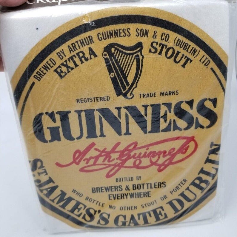 May include: A Guinness Stout label, featuring a gold and black oval design with the Guinness logo and text. The label includes the words "Brewed by Arthur Guinness Son & Co. (Dublin) Ltd." and "Extra Stout."
