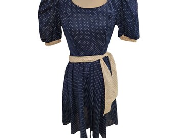 May include: A navy blue dress with white polka dots and a cream-coloured sash. The dress has puffed sleeves and a fitted bodice.