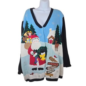 May include: A Christmas-themed sweater with a V-neck and long black sleeves. The front features Santa Claus, a snowy landscape, and directional signs reading "Reindeer," "Santa," "Believers," "Workshop," and "Elves."