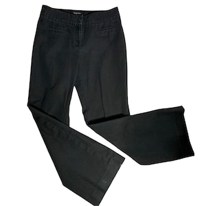 May include: Black wide-leg pants with a straight fit from the waist to the knee, then widening to a wide leg opening. The pants have a zipper fly and button closure, belt loops, and two front pockets.