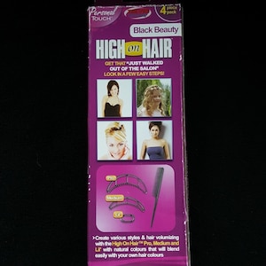 May include: A purple and black box for the "High on Hair" product. The box features images of women with styled hair, a comb, and hair volumizing tools. Text on the box includes "Black Beauty" and "Get that 'just walked out of the salon' look in a few easy steps!"