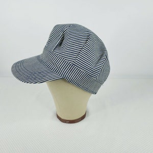 May include: A blue and white striped cotton cap with a short brim. The cap is on a white mannequin head.
