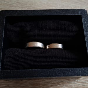 以下が含まれることがあります： 黒いベルベットのリングボックスに入った2つの銀の結婚指輪