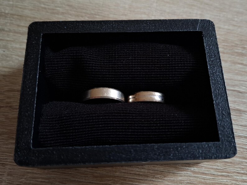 以下が含まれることがあります： 黒いベルベットのリングボックスに入った2つの銀の結婚指輪