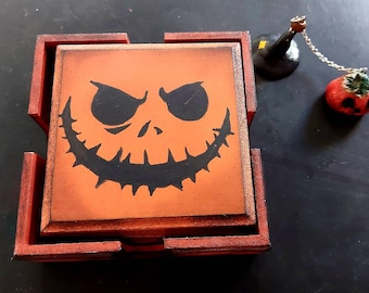 May include: A set of four orange and red wooden coasters featuring a black jack-o'-lantern face design. The coasters are stacked on top of each other.