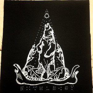 May include: Black and white embroidered patch featuring a wolf howling at the moon with a skull and crossbones design. The patch is on a black fabric background.