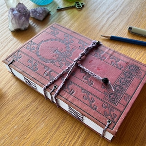 Puede incluir: Una taza de cerámica blanca con asa negra y el texto "But First, Coffee" en negrita negra. La taza está sobre un fondo borroso. La taza mide aproximadamente 10 cm de altura.