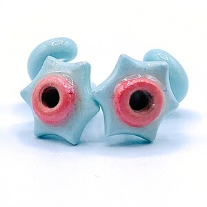 May include: Two light blue star-shaped ceramic earrings with a pink center hole.