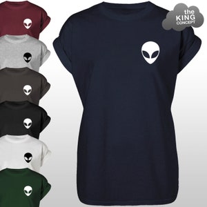 Pode incluir: Uma camiseta azul marinho com um gráfico de rosto de alienígena branco na frente. A camiseta tem mangas dobradas e um decote redondo.